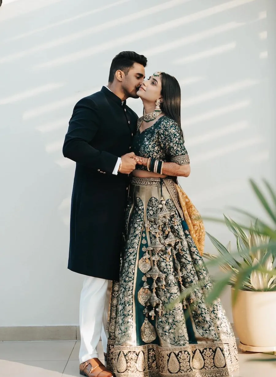 Couple in contemporary Indian wedding attire in a sunlit room